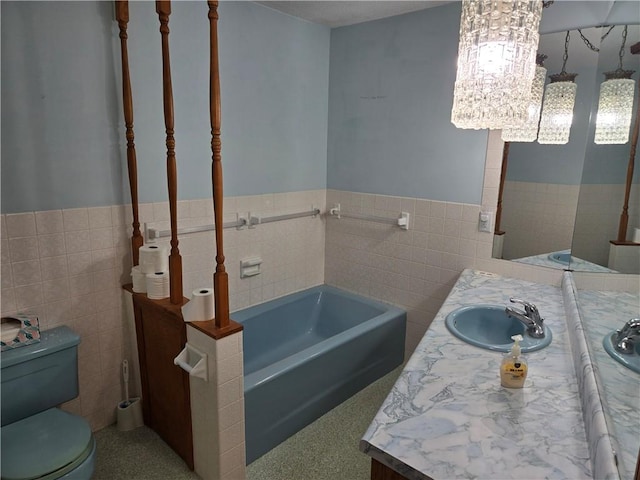 bathroom with tile walls, a tub to relax in, vanity, and toilet