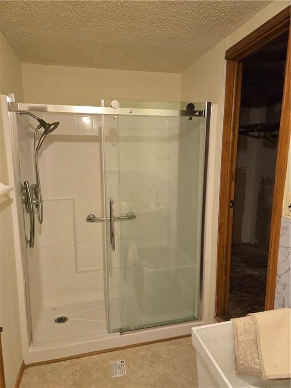 bathroom with a textured ceiling and an enclosed shower