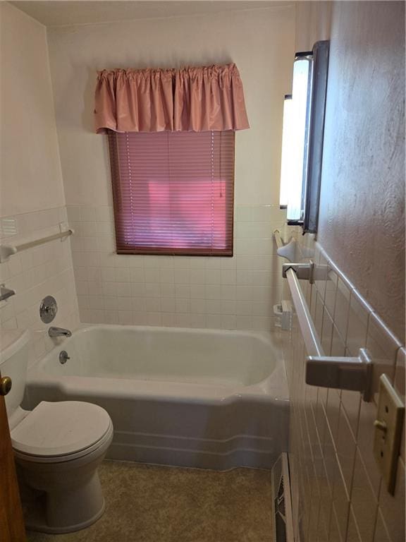 bathroom featuring tile walls, tiled shower / bath combo, and toilet