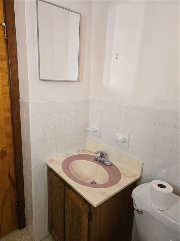 bathroom with vanity, tile walls, and toilet