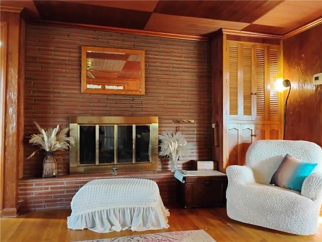 living area with a fireplace, wood ceiling, hardwood / wood-style flooring, and wood walls