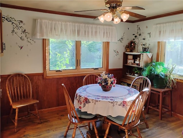 dining room with ceiling fan, hardwood / wood-style flooring, ornamental molding, and wood walls