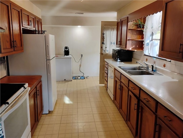 kitchen featuring backsplash, sink, white appliances, and washer / dryer