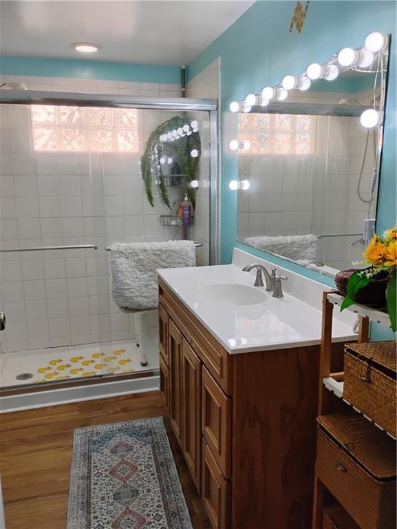 bathroom with vanity, wood-type flooring, a healthy amount of sunlight, and walk in shower