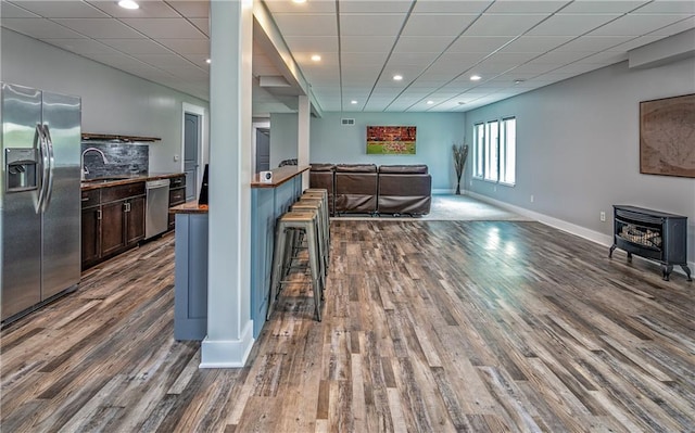 kitchen featuring dark hardwood / wood-style floors, appliances with stainless steel finishes, dark brown cabinetry, and a wood stove