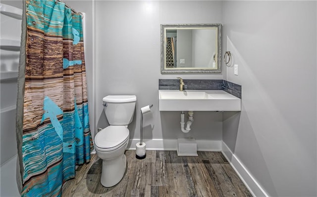 full bathroom featuring hardwood / wood-style floors, shower / bath combination with curtain, toilet, and sink