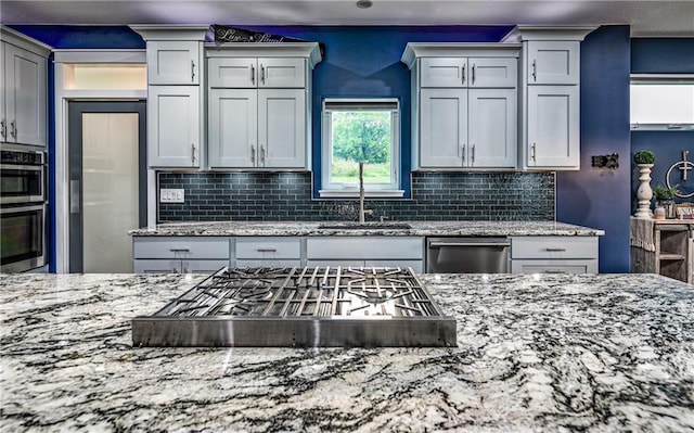 kitchen with light stone counters, stainless steel appliances, and backsplash