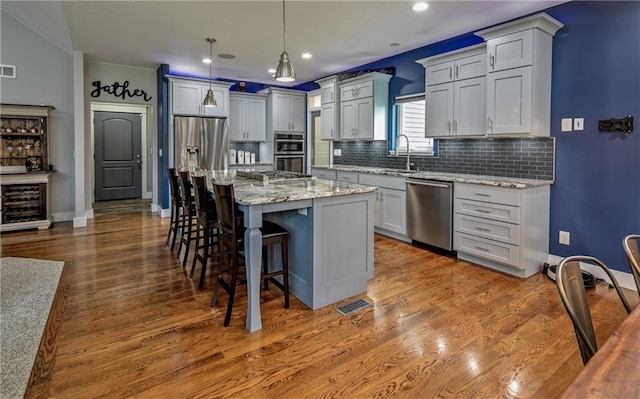 kitchen with sink, a center island, hanging light fixtures, appliances with stainless steel finishes, and a kitchen breakfast bar