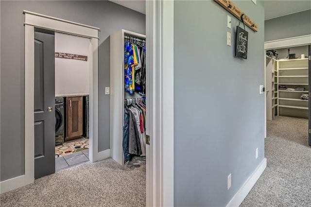 hallway with washer / clothes dryer and light colored carpet