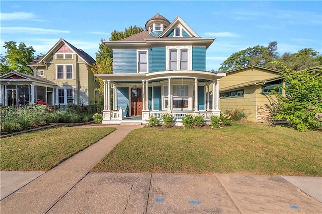 victorian house featuring a front lawn and covered porch