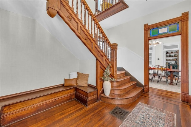 stairs with wood-type flooring and a notable chandelier