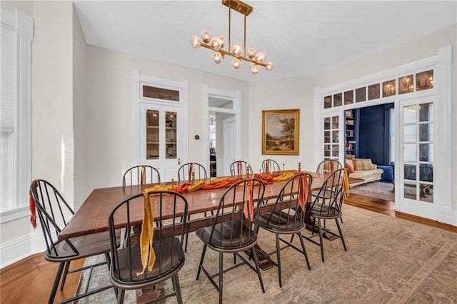 dining space featuring wood-type flooring and a notable chandelier