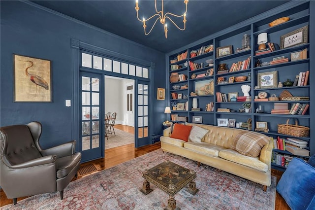 sitting room with wood-type flooring, crown molding, and a chandelier