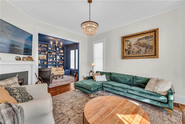 living room with built in shelves, hardwood / wood-style floors, and a chandelier