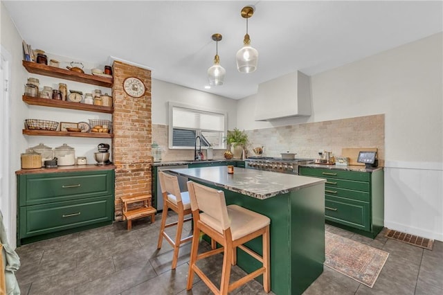 kitchen featuring wall chimney exhaust hood, a kitchen breakfast bar, green cabinets, sink, and appliances with stainless steel finishes