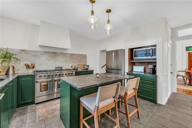 kitchen with appliances with stainless steel finishes, green cabinetry, a breakfast bar area, and a center island