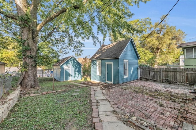 rear view of house with a storage unit and a patio area