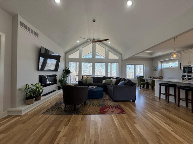 living area featuring visible vents, a ceiling fan, lofted ceiling, light wood-type flooring, and recessed lighting