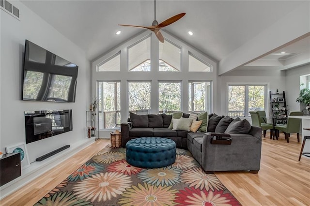 living area with high vaulted ceiling, light wood-type flooring, visible vents, and recessed lighting