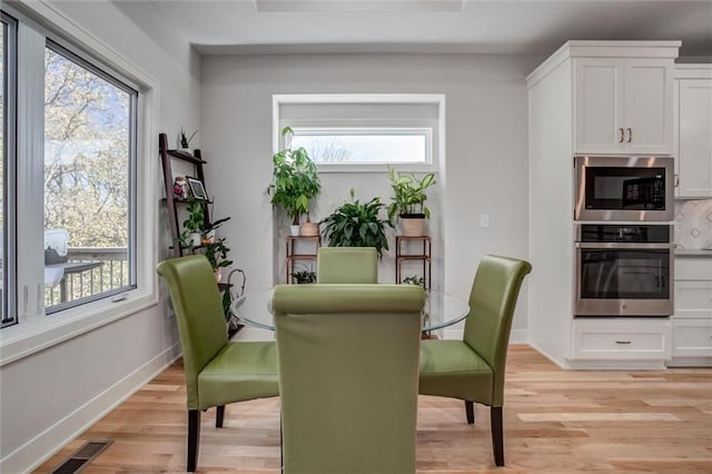 dining area with baseboards, visible vents, and light wood-style floors