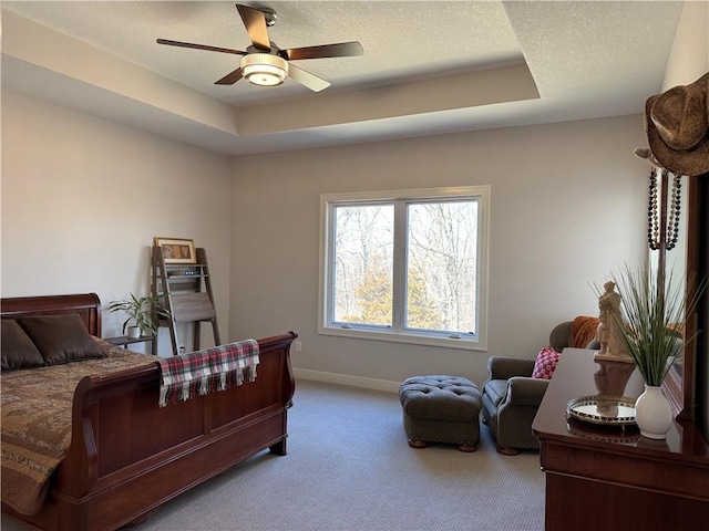 bedroom with baseboards, ceiling fan, carpet, a tray ceiling, and a textured ceiling