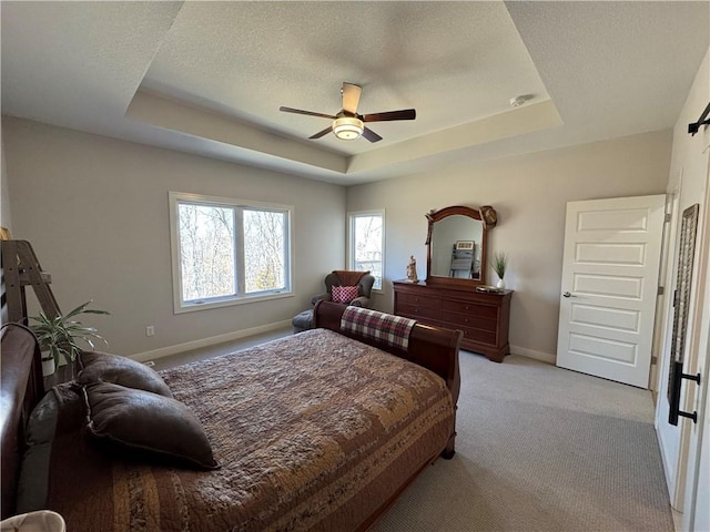 bedroom featuring baseboards, a raised ceiling, light colored carpet, ceiling fan, and a textured ceiling