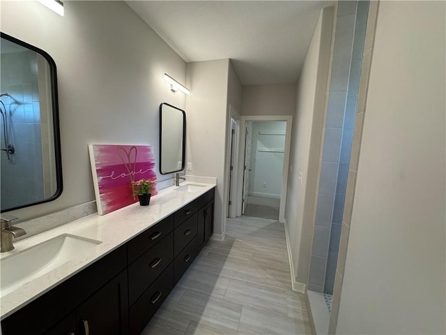 bathroom featuring double vanity, a sink, and tiled shower