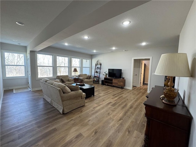 living room featuring recessed lighting, a textured ceiling, baseboards, and wood finished floors