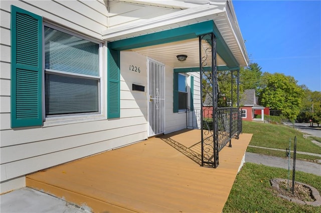 view of exterior entry with a lawn and covered porch