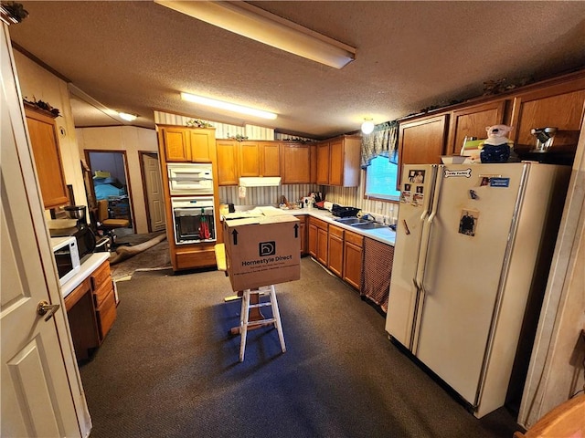 kitchen featuring a textured ceiling, white appliances, a center island, and lofted ceiling