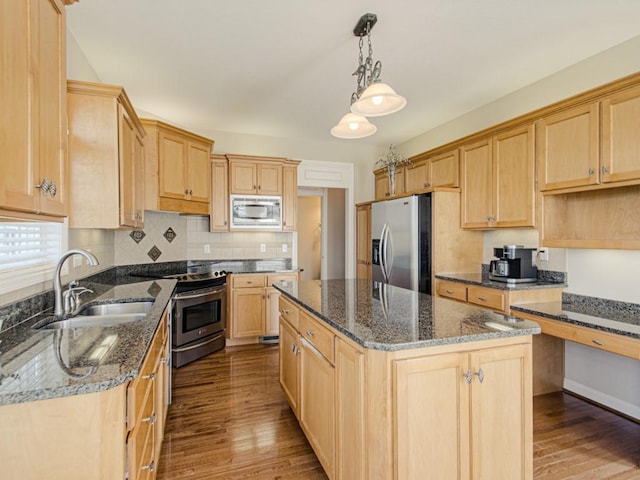 kitchen with a kitchen island, appliances with stainless steel finishes, sink, dark stone counters, and hanging light fixtures