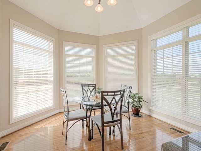 dining space featuring plenty of natural light, light hardwood / wood-style floors, vaulted ceiling, and a notable chandelier