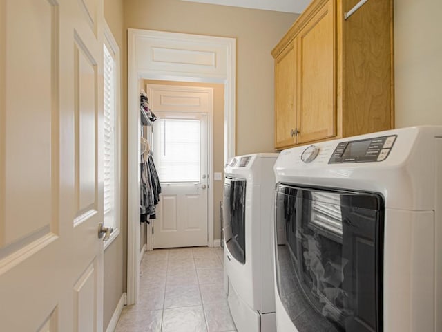 laundry room with cabinets, light tile patterned floors, and washing machine and clothes dryer