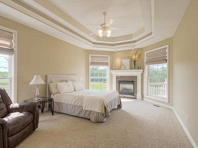 carpeted bedroom with ceiling fan and a tray ceiling