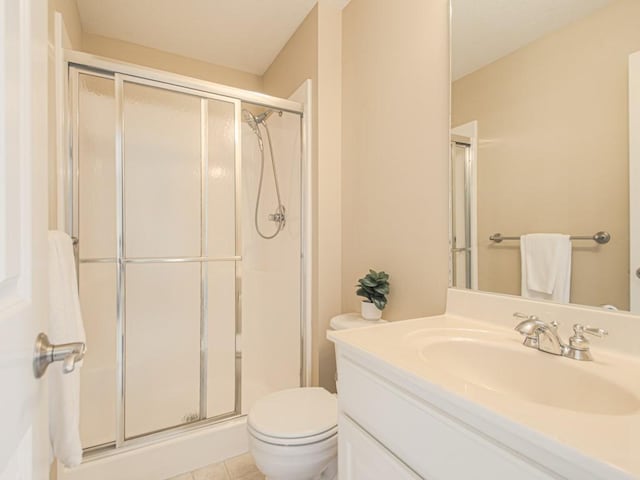 bathroom featuring a shower with door, vanity, tile patterned flooring, and toilet