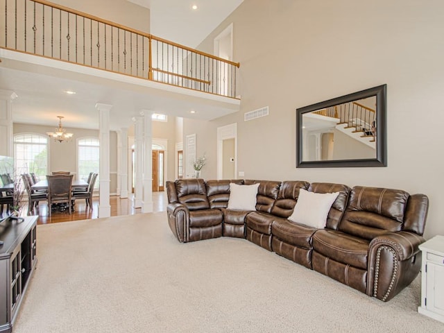 living room featuring decorative columns, carpet, a high ceiling, and a notable chandelier