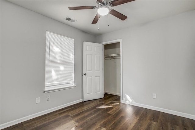 unfurnished bedroom featuring dark hardwood / wood-style flooring, a closet, multiple windows, and ceiling fan