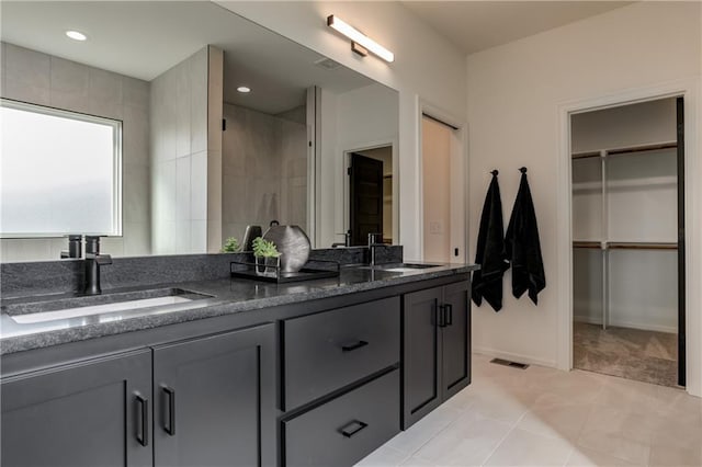 bathroom featuring vanity, tiled shower, and tile patterned flooring