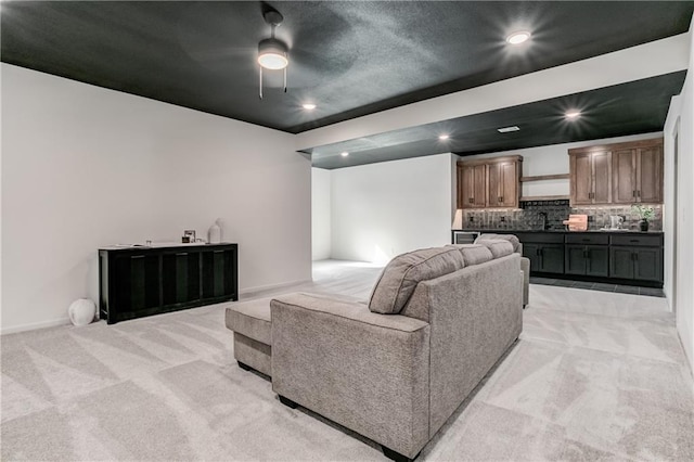 carpeted living room featuring ceiling fan and sink