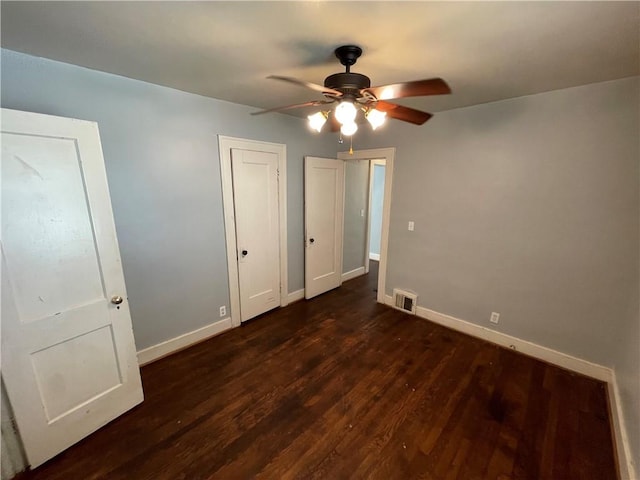 unfurnished bedroom with ceiling fan and dark wood-type flooring