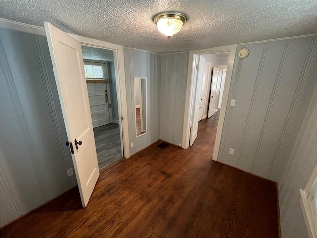 hall with a textured ceiling and dark hardwood / wood-style flooring