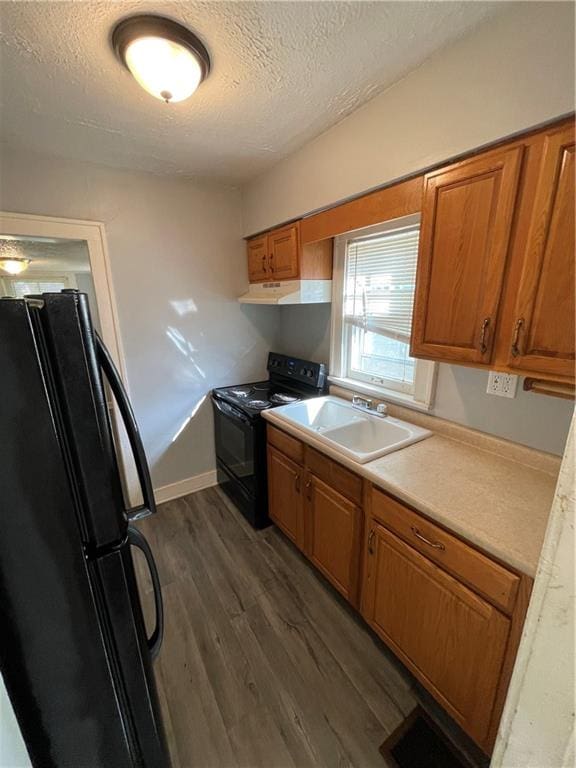 kitchen with a textured ceiling, dark wood-type flooring, sink, and black appliances