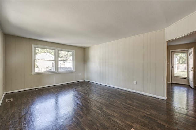 unfurnished room with dark hardwood / wood-style flooring and wooden walls