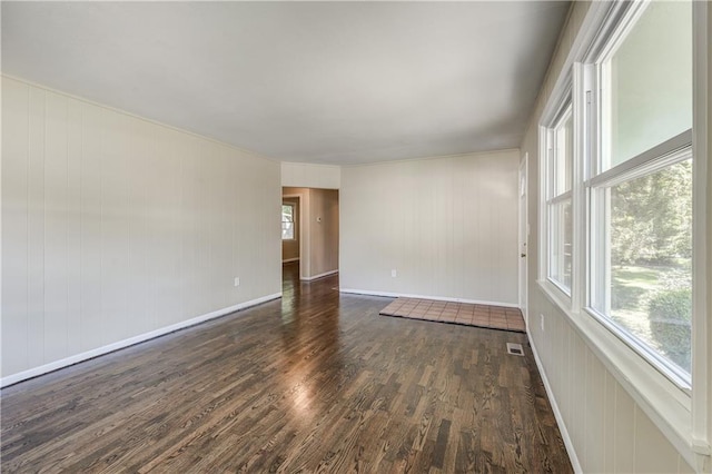 empty room with dark wood-type flooring and wooden walls