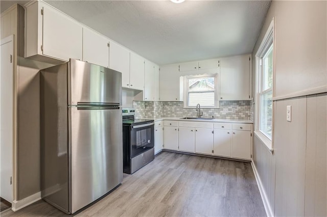 kitchen featuring backsplash, white cabinetry, light wood-type flooring, sink, and stainless steel appliances