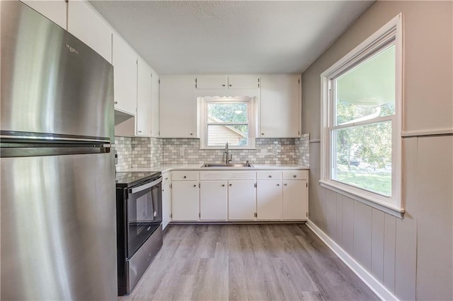 kitchen featuring light hardwood / wood-style flooring, stainless steel appliances, backsplash, sink, and white cabinets