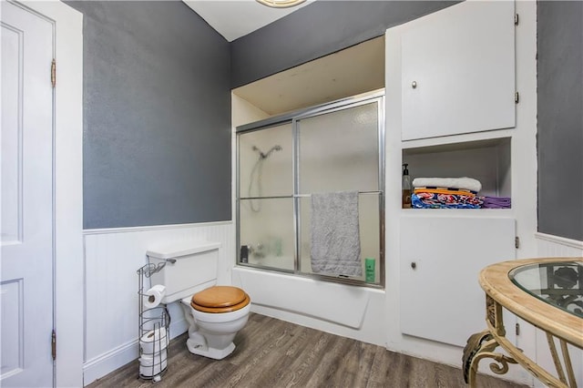 bathroom with enclosed tub / shower combo, toilet, and wood-type flooring