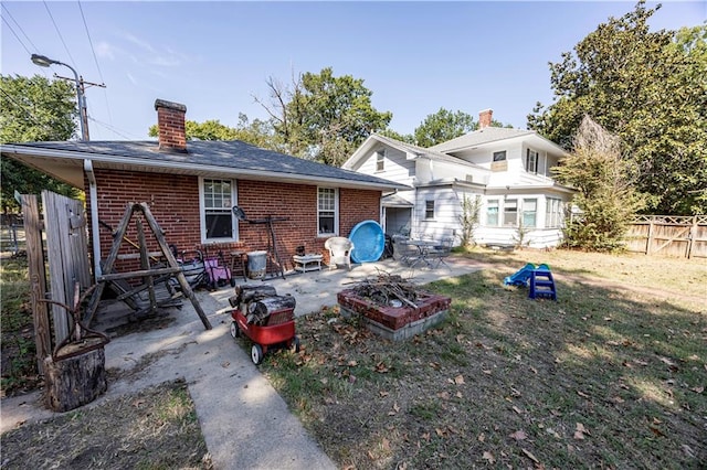 rear view of property with an outdoor fire pit, a yard, and a patio area