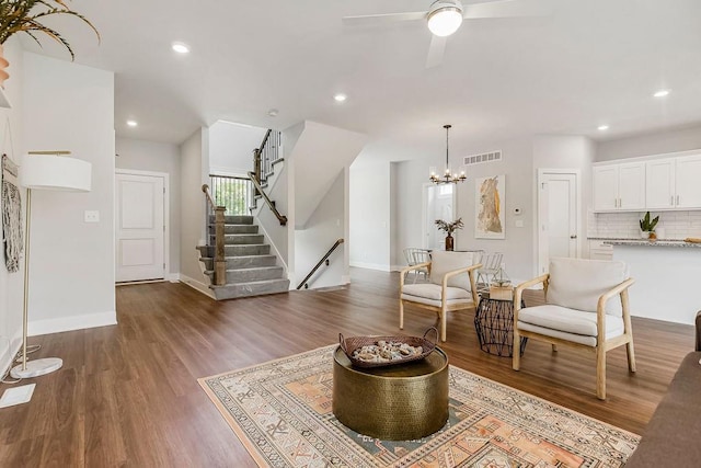 living area with dark wood-type flooring and ceiling fan with notable chandelier