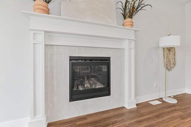 room details featuring a tiled fireplace and wood-type flooring